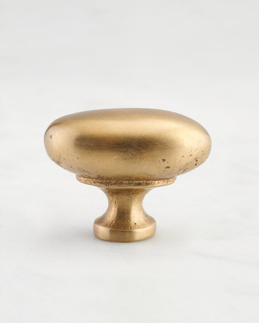 A 'Large' oval-shaped knob for a kitchen cupboard or drawer with an aged brass finish and unique dented textures that makes it look like a beloved, well aged brass from centuries ago.