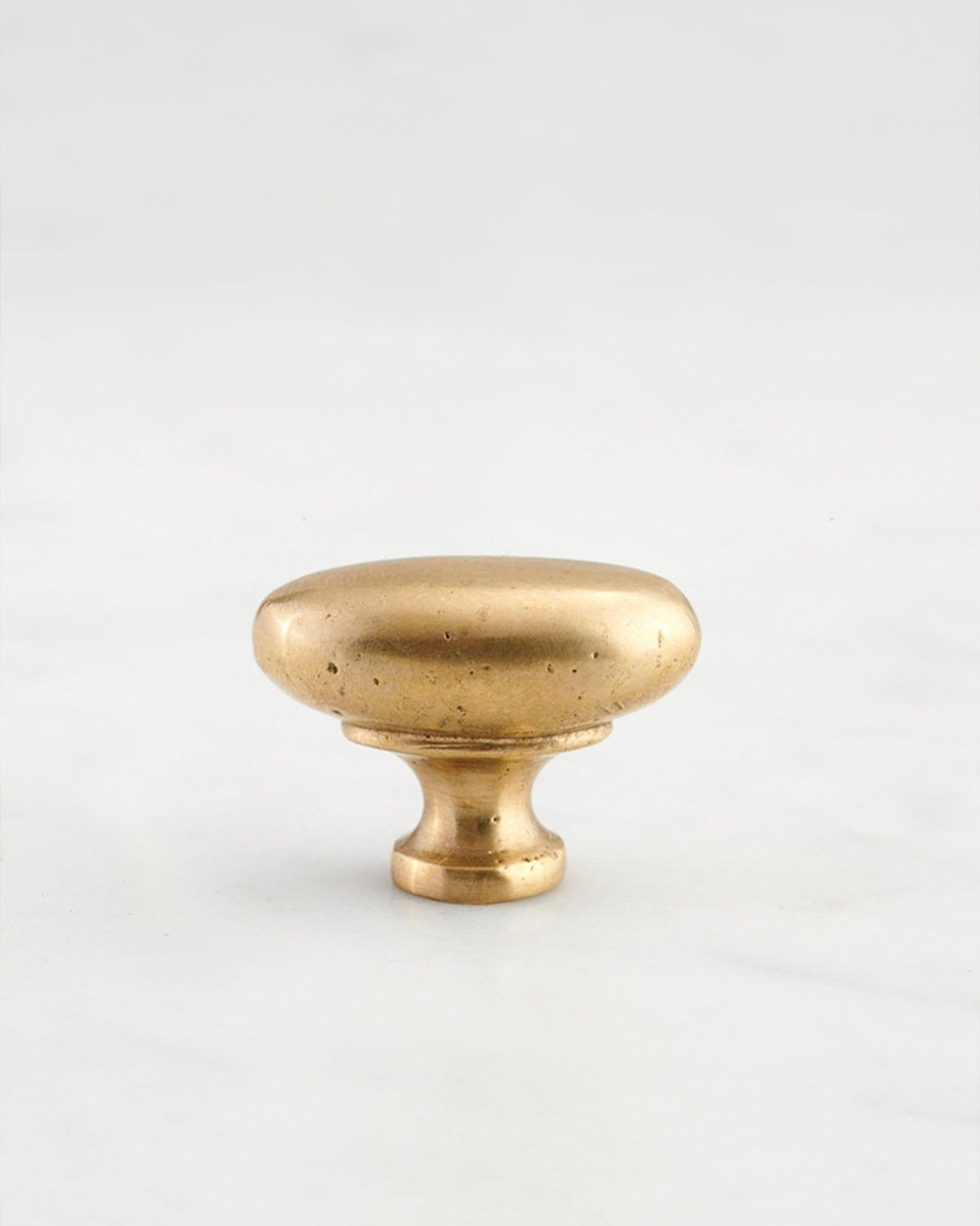 A 'Small' oval-shaped knob for a kitchen cupboard or drawer with an aged brass finish and unique dented textures that makes it look like a beloved, well aged brass from centuries ago. TEST