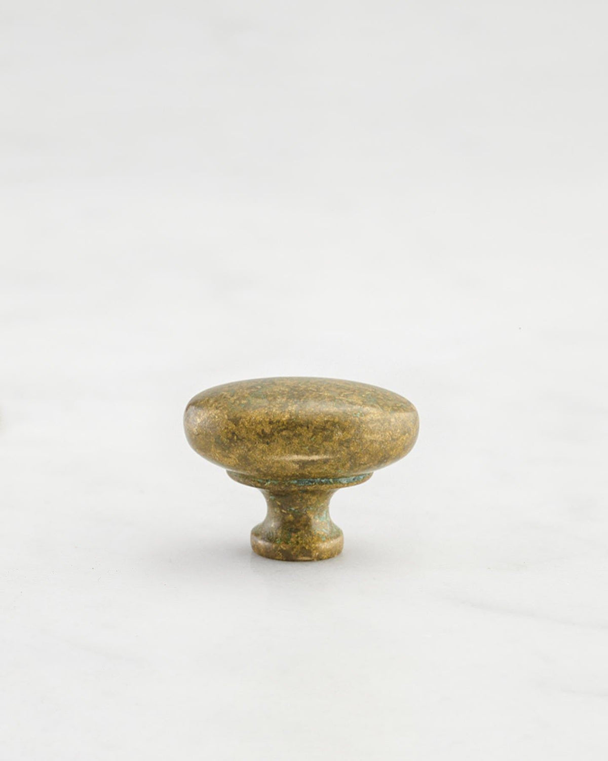 A 'Petite' oval-shaped knob for a kitchen cupboard or drawer with an aged verdigris brass finish and unique dented textures as if was made by an artisan blacksmith centuries ago. TEST