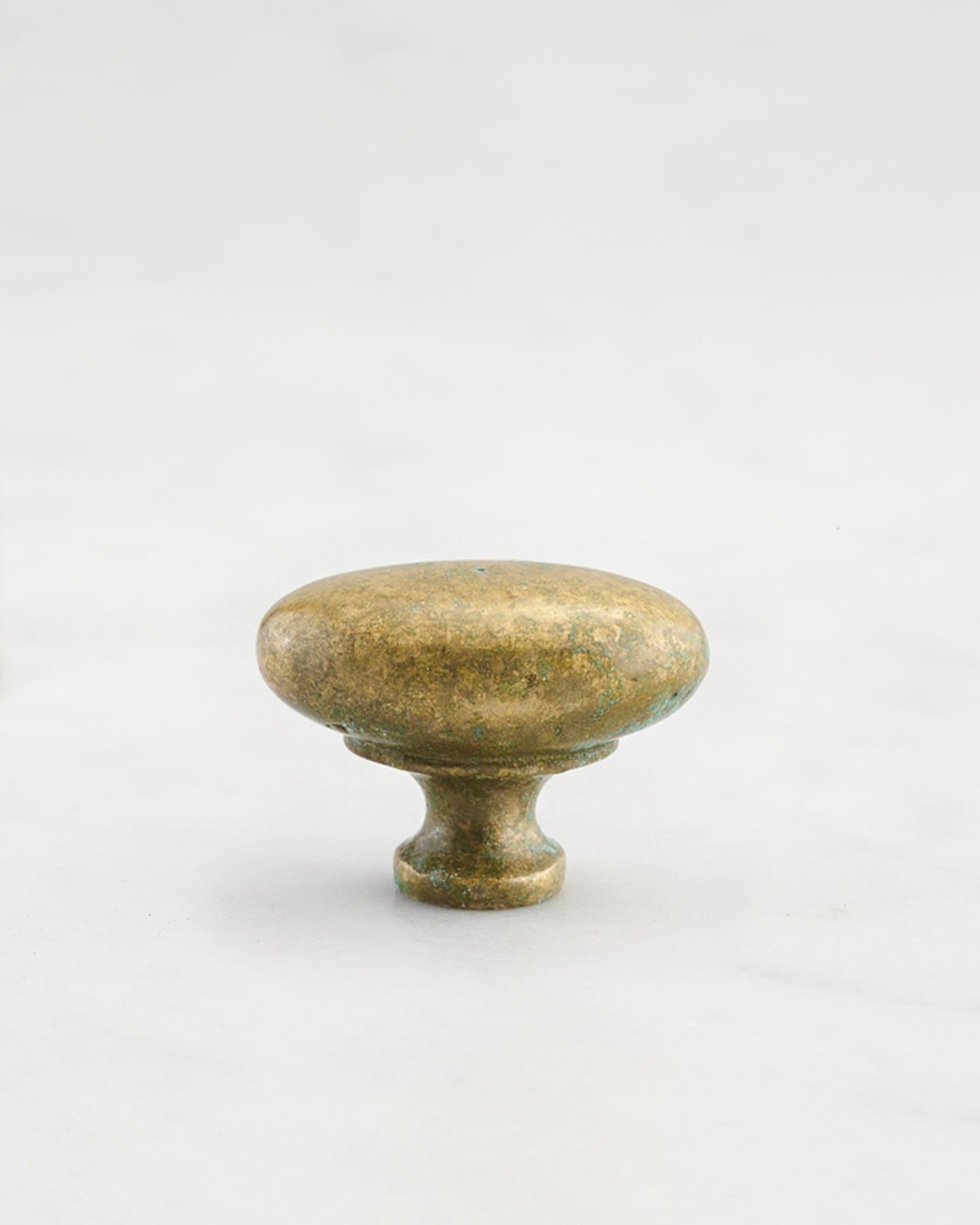 A 'Small' oval-shaped knob for a kitchen cupboard or drawer with an aged verdigris brass finish and unique dented textures as if was made by an artisan blacksmith centuries ago.