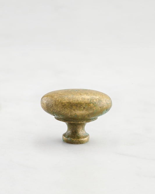 A 'Small' oval-shaped knob for a kitchen cupboard or drawer with an aged verdigris brass finish and unique dented textures as if was made by an artisan blacksmith centuries ago.