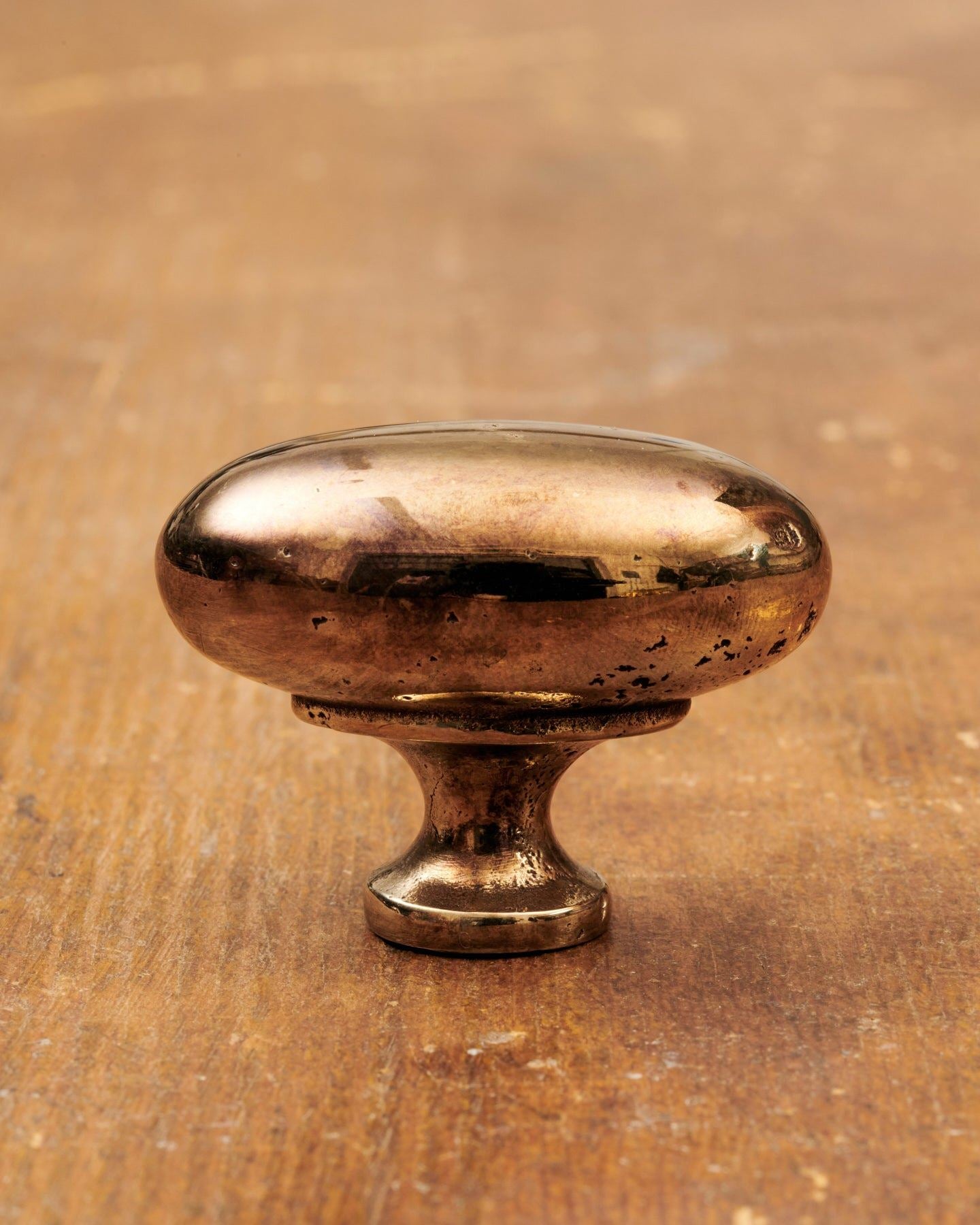 A 'Large' oval-shaped knob for a kitchen cupboard or drawer with a warm burnished brass finish and unique dented textures as if was made by an artisan blacksmith centuries ago.