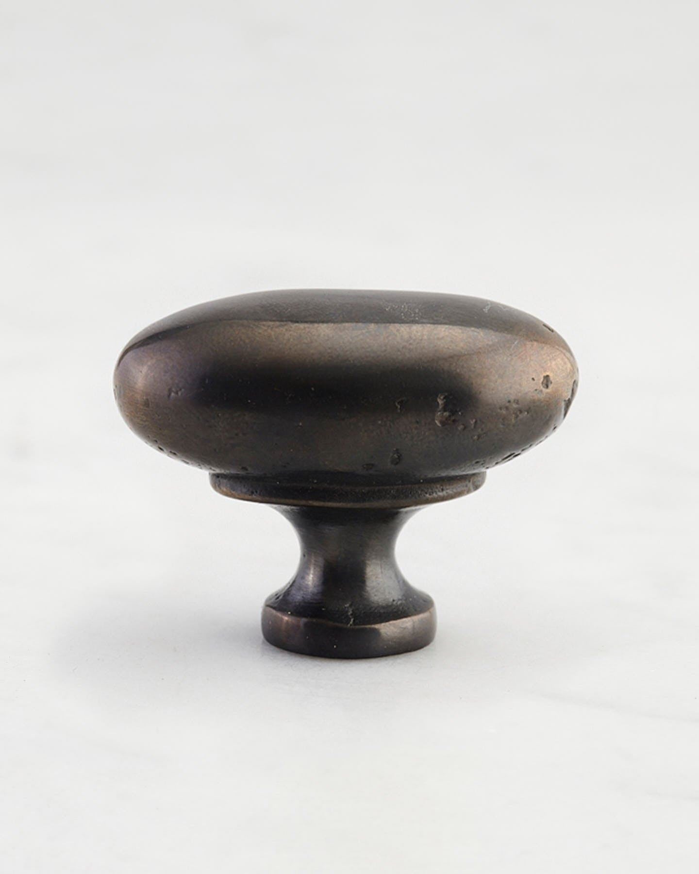 A 'Large' oval-shaped knob for a kitchen cupboard or drawer with a dark oxidised bronze finish  and unique dented textures as if was made by an artisan blacksmith centuries ago.