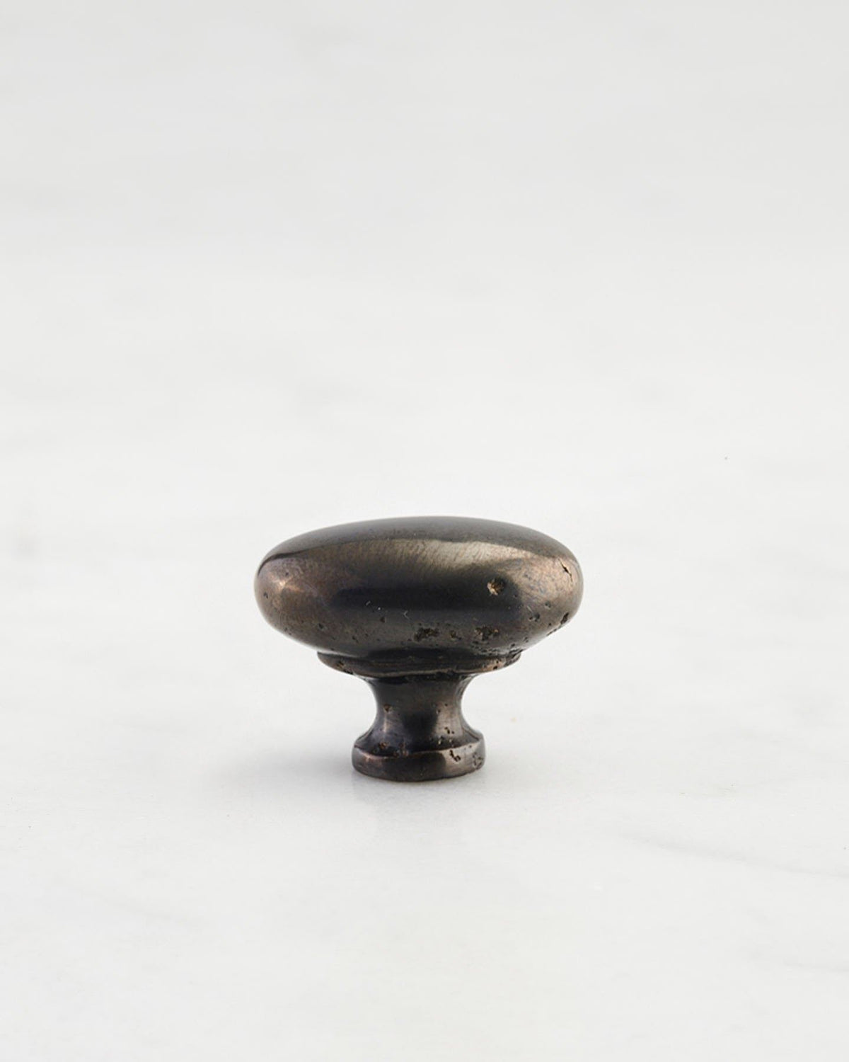 A 'Petite' oval-shaped knob for a kitchen cupboard or drawer with a dark oxidised bronze finish that makes it look like a beloved, well aged brass from centuries ago. TEST