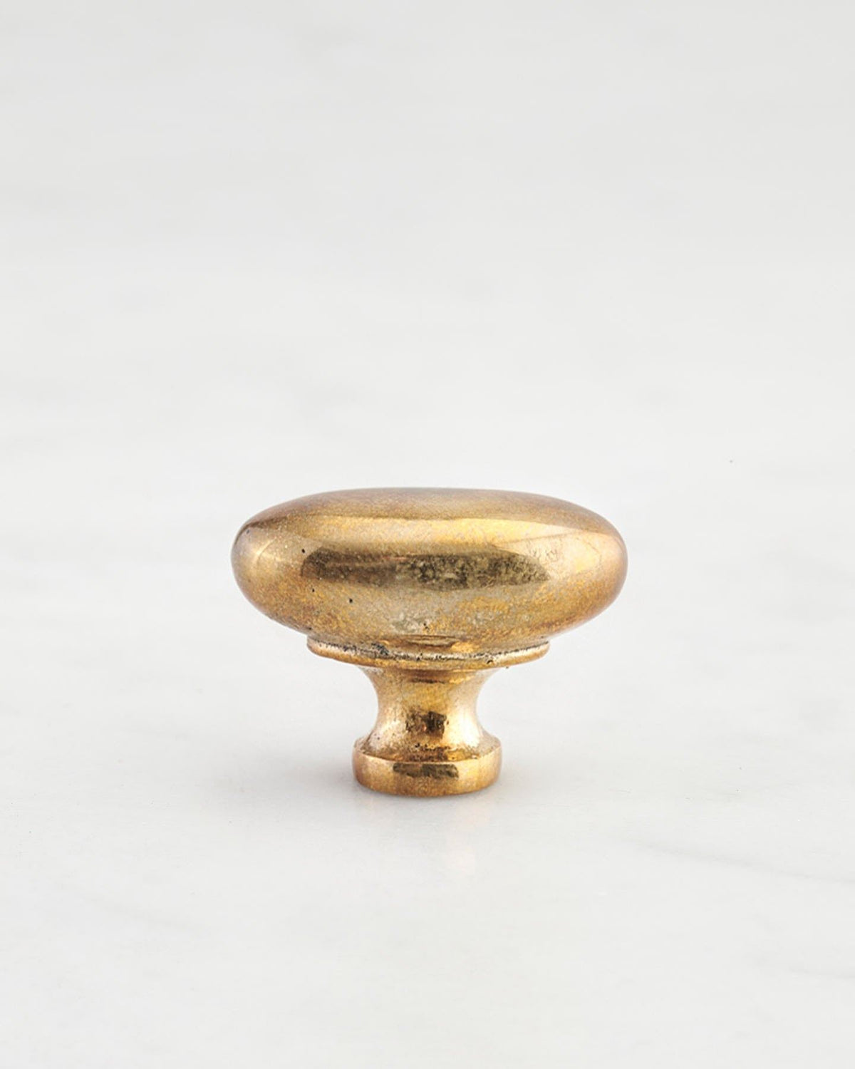 A 'Small' oval-shaped knob for a kitchen cupboard or drawer with a bright polished bronze finish and unique dented textures that makes it look like a beloved, well aged bronze from centuries ago. TEST