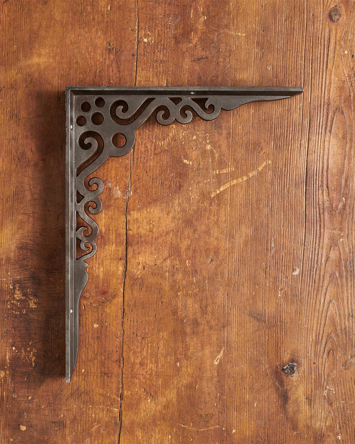 A side profile view of a large Victorian-inspired ornate shelf bracket in a cast iron finish. TEST