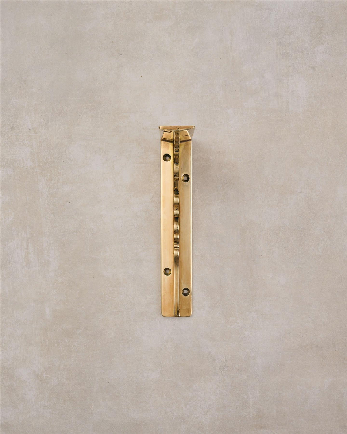 A front profile view of a small Victorian-inspired ornate shelf bracket in a warm polished brass finish. TEST