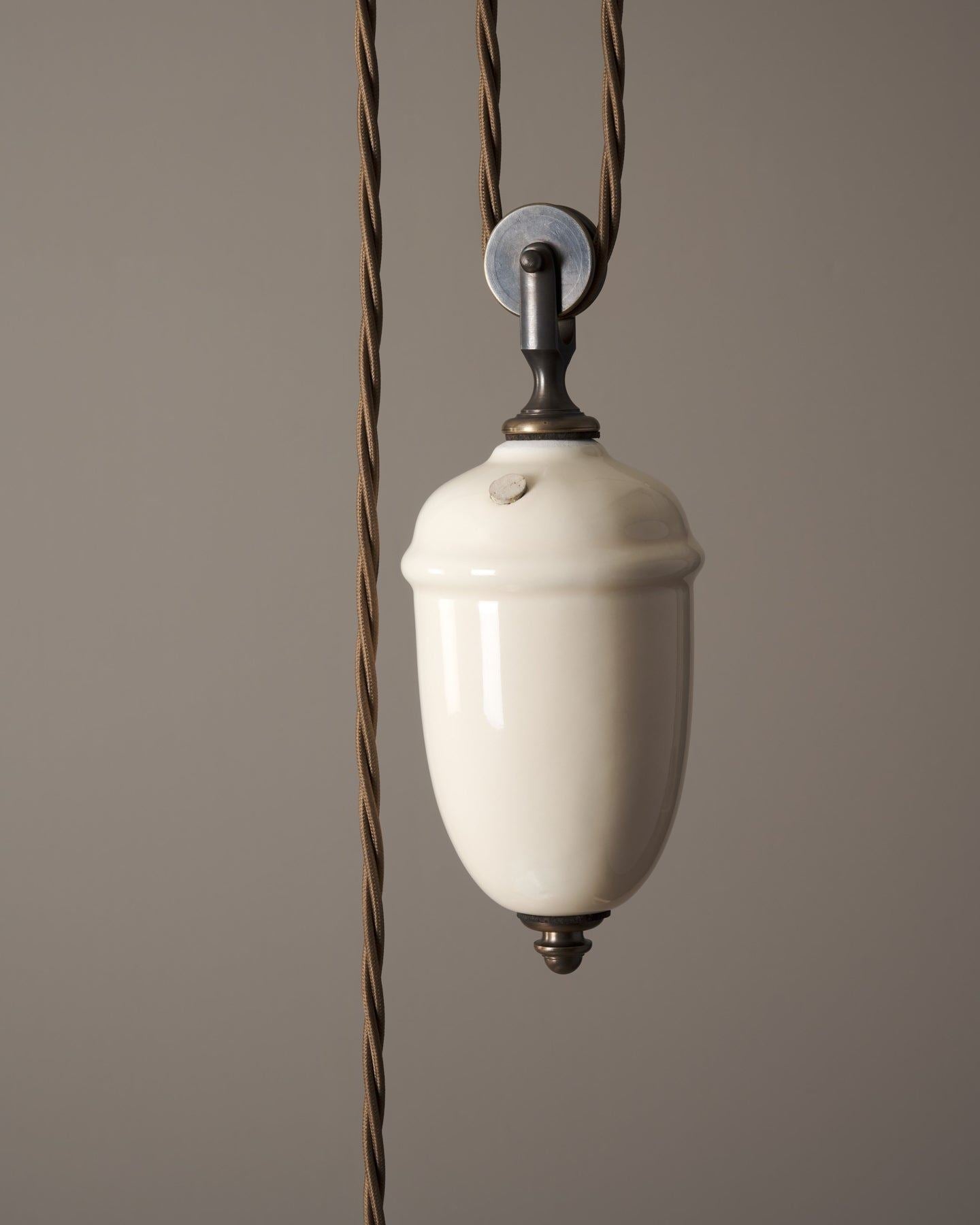 A close-up view of a cream glazed ceramic counterweight for a rise and fall light.