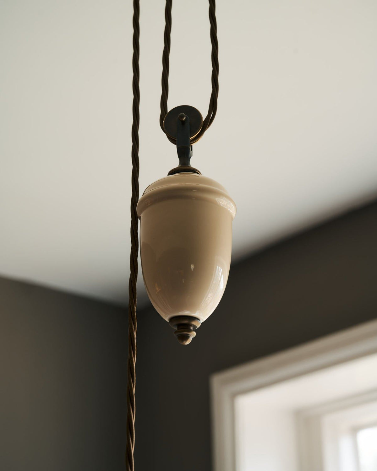 A close-up view of a cream glazed ceramic counterweight for a rise and fall light. TEST