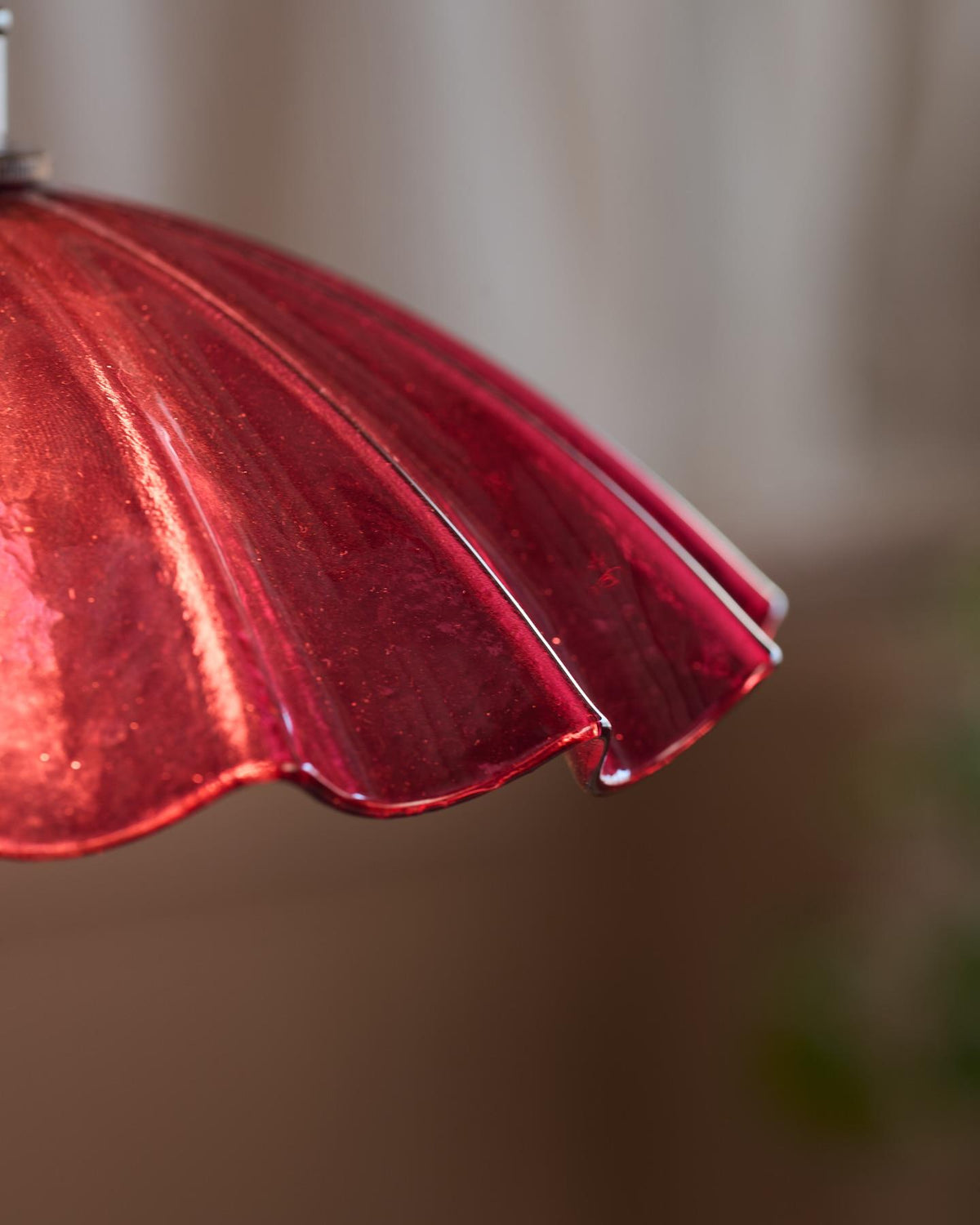 A close-up view of a small frilly cranberry glass light shade. TEST
