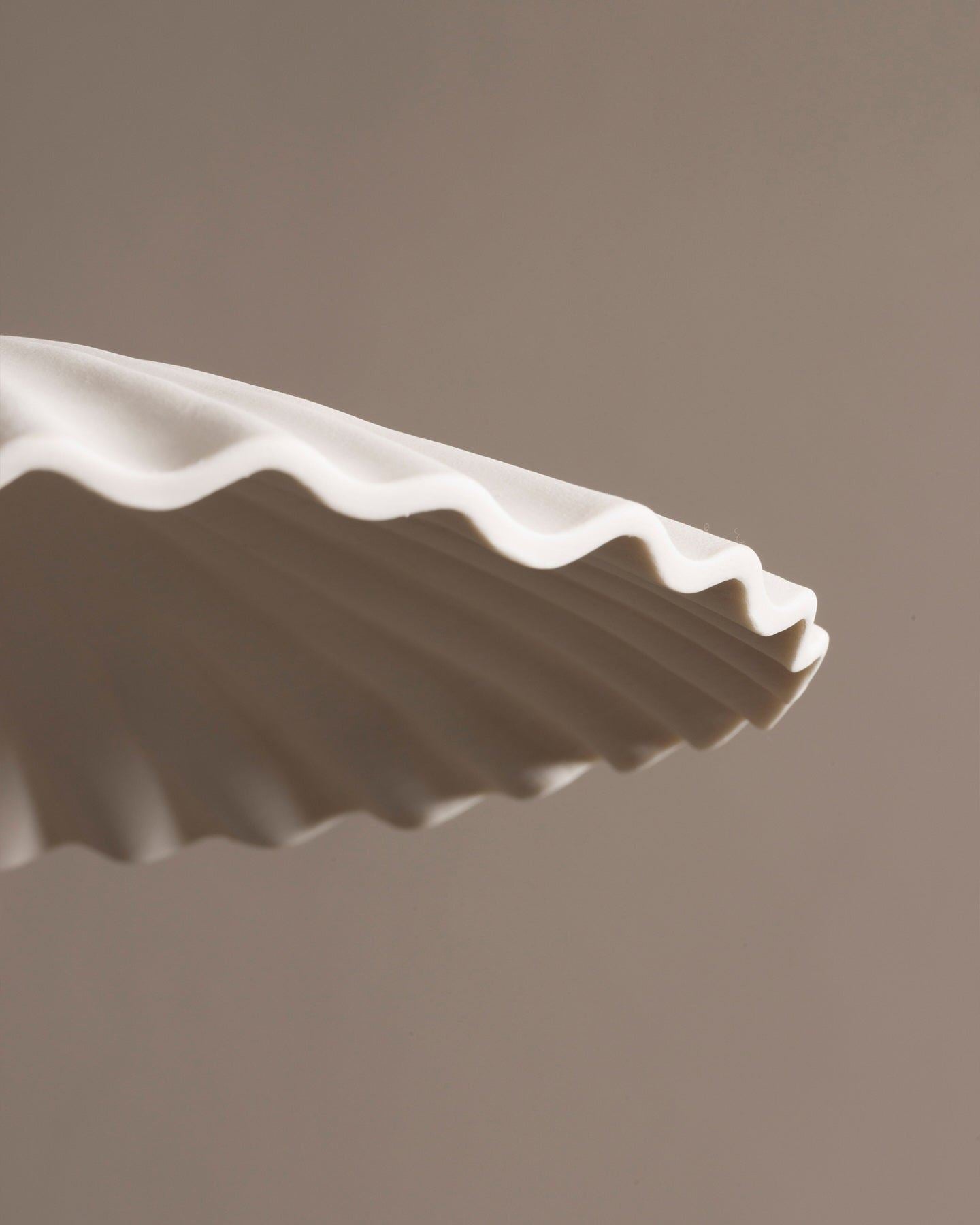 A close-up view of an unglazed porcelain pendant light with narrow pleats.