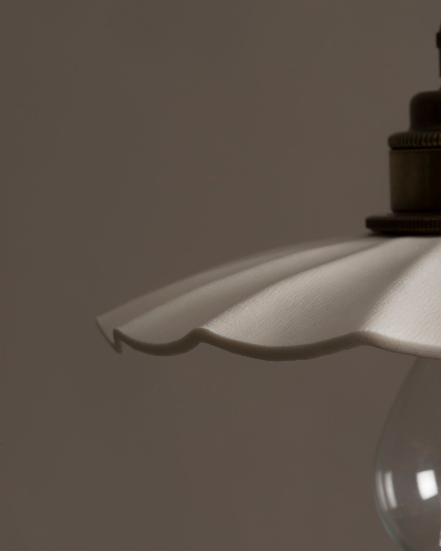 A close-up view of an unglazed porcelain pendant light with wide pleats.
