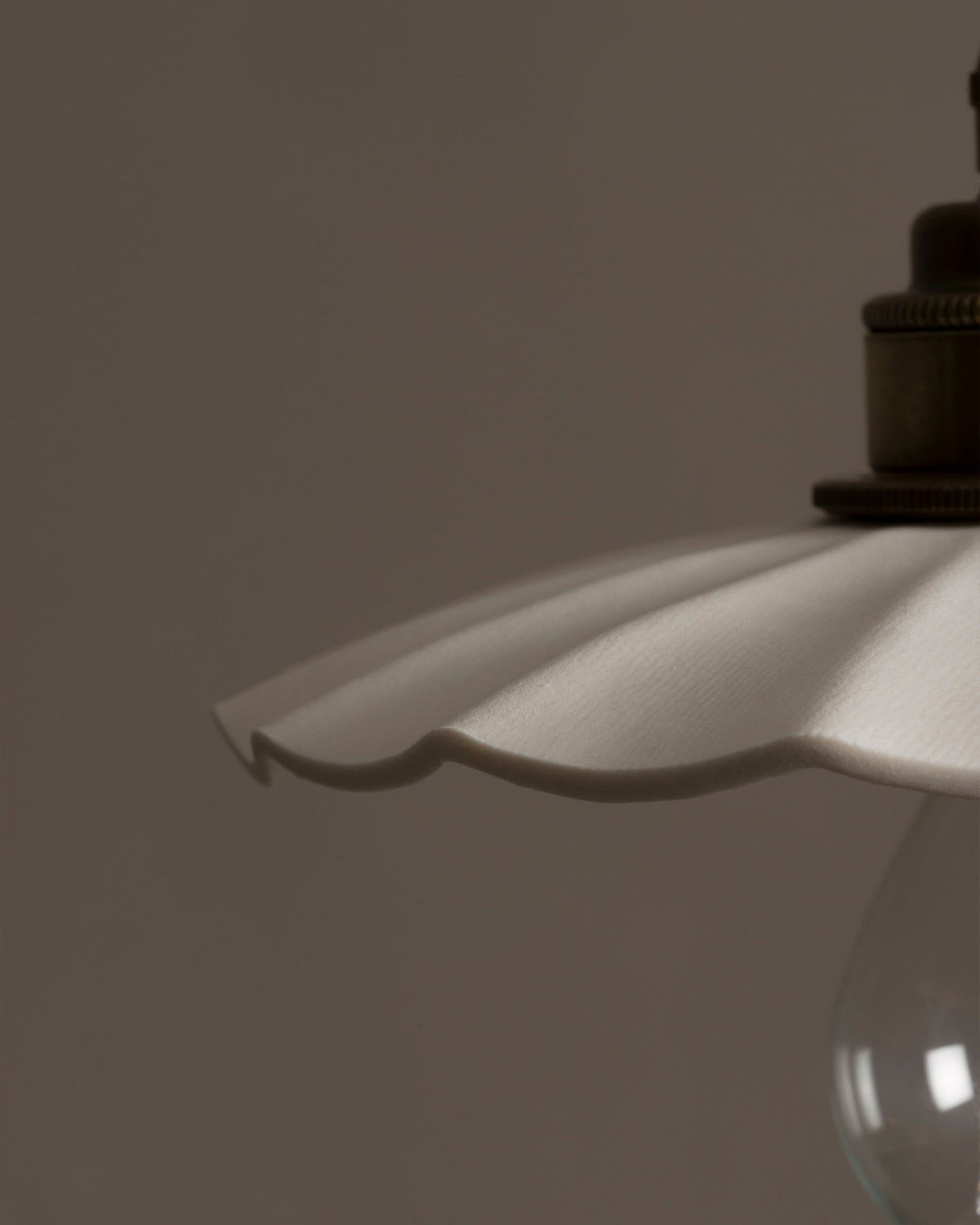 A close-up view of an unglazed porcelain pendant light with wide pleats. TEST