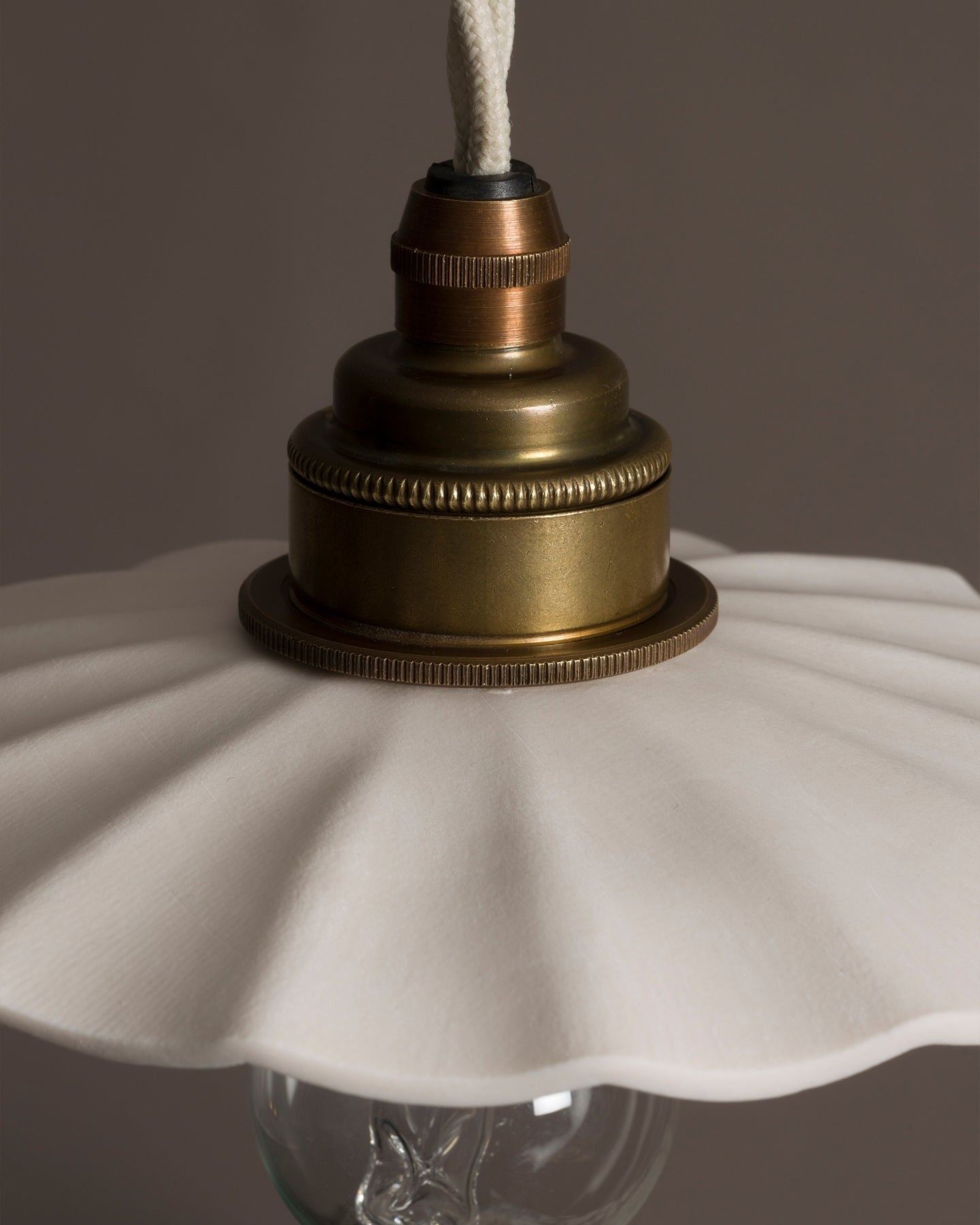 A close-up view of an unglazed porcelain pendant light with wide pleats.