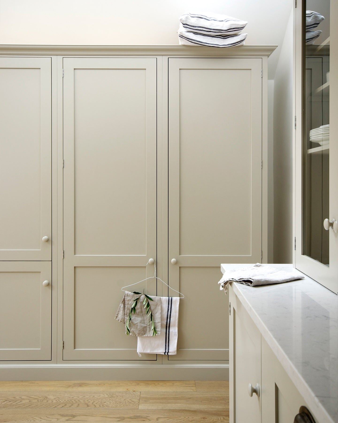 A straight-on view of simple Shaker-style tall pantry cupboards painted in a creamy mushroom colour.