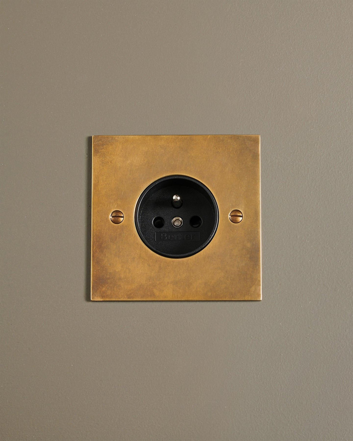 An oblique view of a classic French-style single plug socket in a warm burnished brass finish. TEST