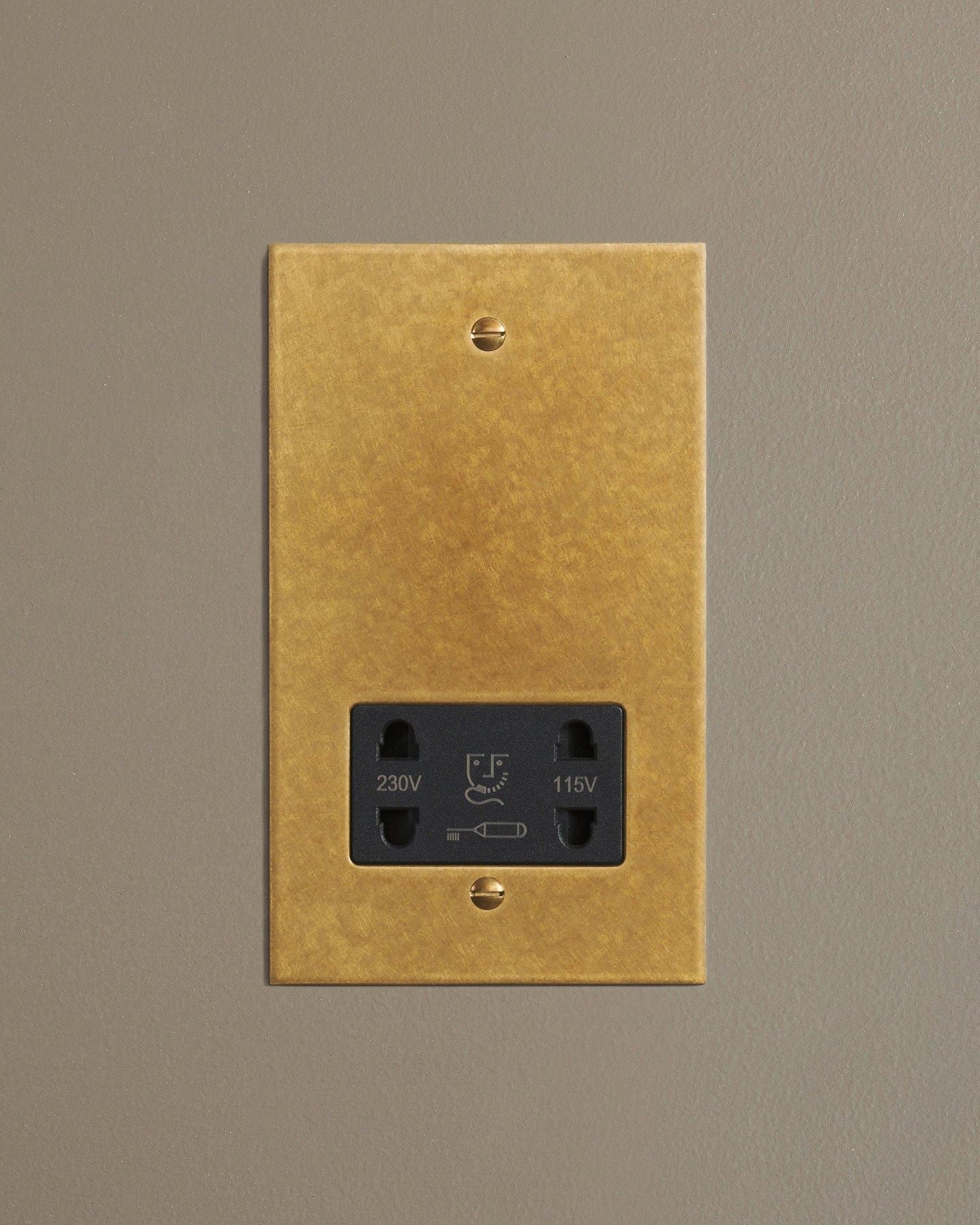 A straight-on view of a classic twin shaver socket in a mottled aged brass finish.
