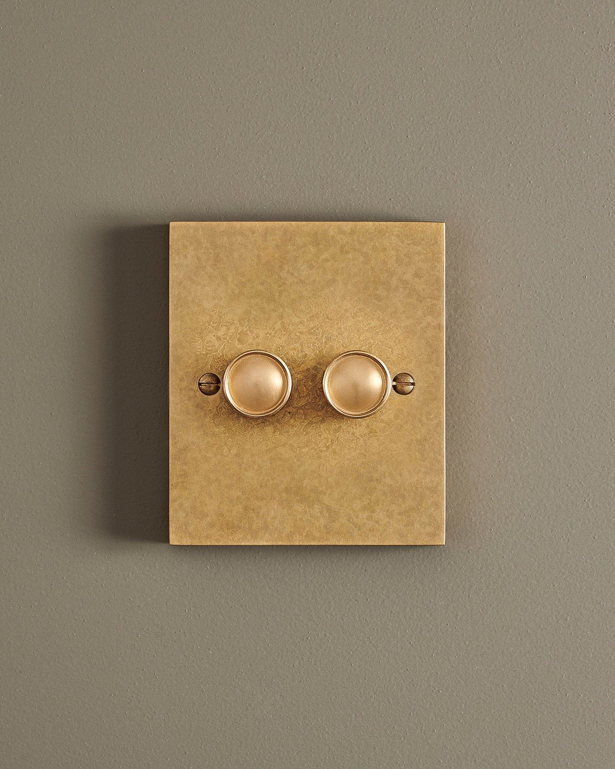 A straight-on view of a 2 gang box dimmer switch in a mottled aged brass finish. TEST