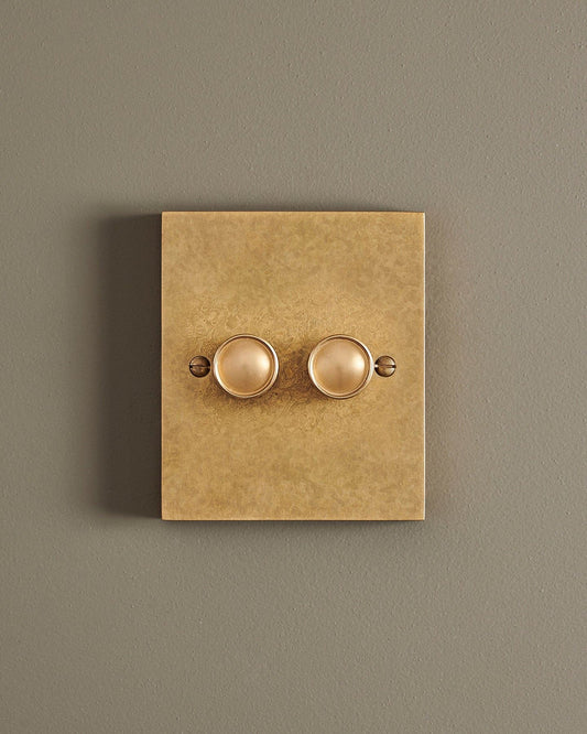 A straight-on view of a 2 gang box dimmer switch in a mottled aged brass finish.