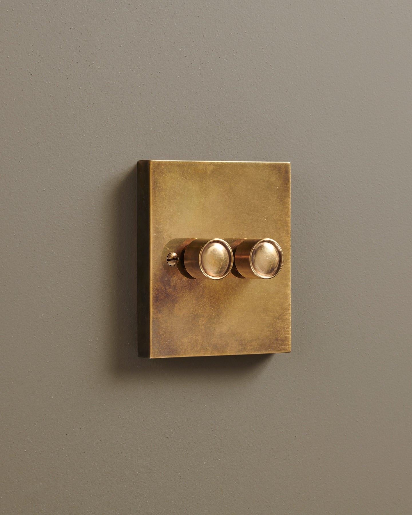 An oblique view of a 2 gang box dimmer switch in a warm burnished brass finish.