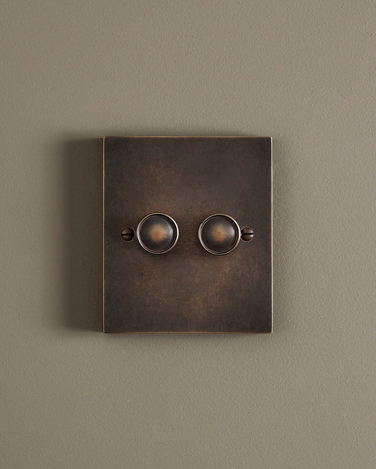 A straight-on view of a 2 gang box dimmer switch in a dark oxidised brass finish.