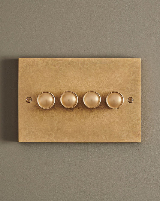 A straight-on view of a 4 gang box dimmer switch in a mottled aged brass finish.