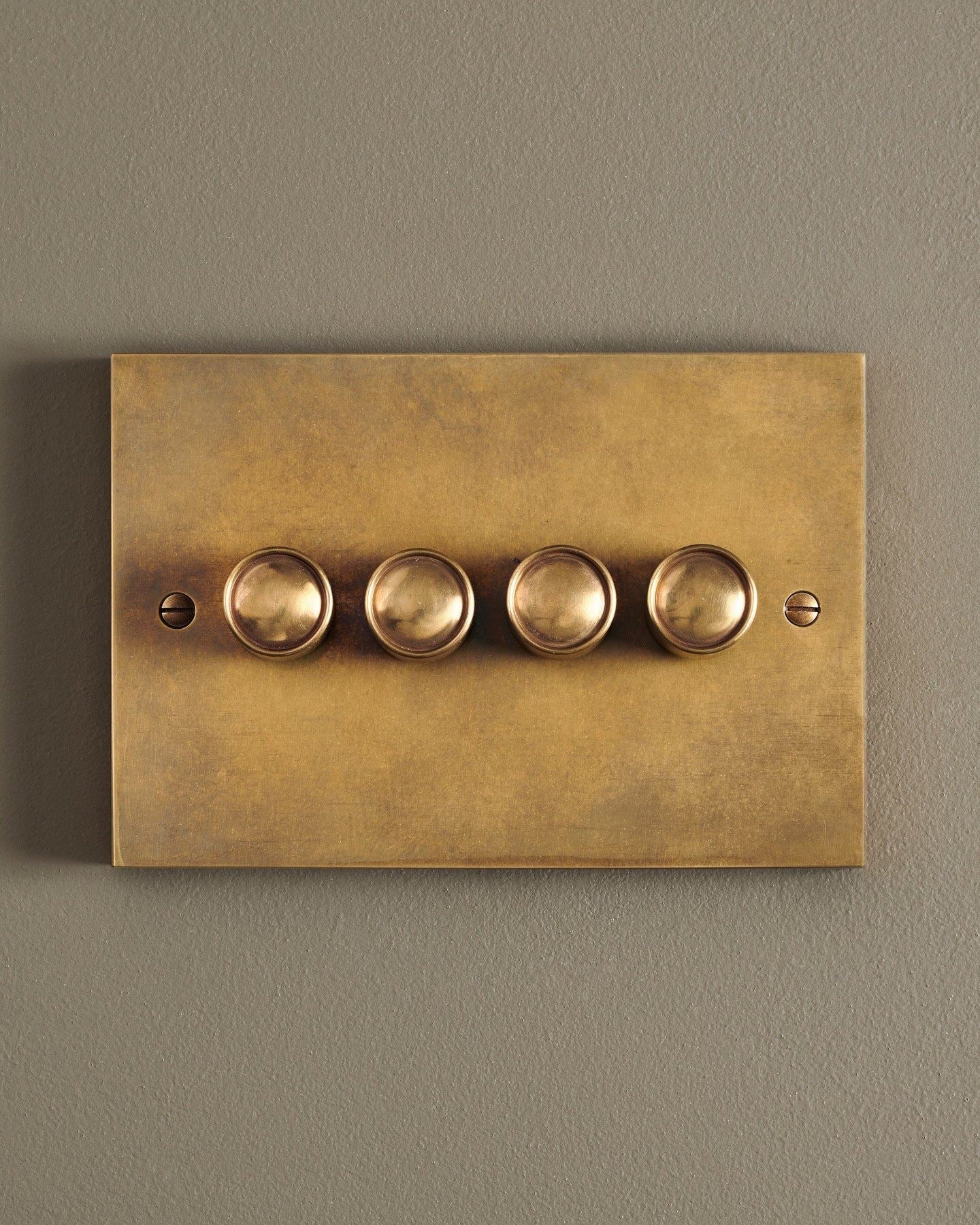 A straight-on view of a 4 gang box dimmer switch in a warm burnished brass finish.
