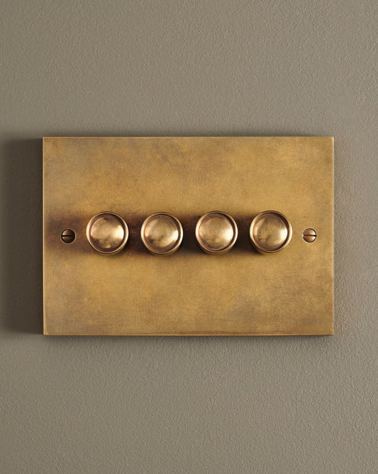 A straight-on view of a 4 gang box dimmer switch in a warm burnished brass finish.