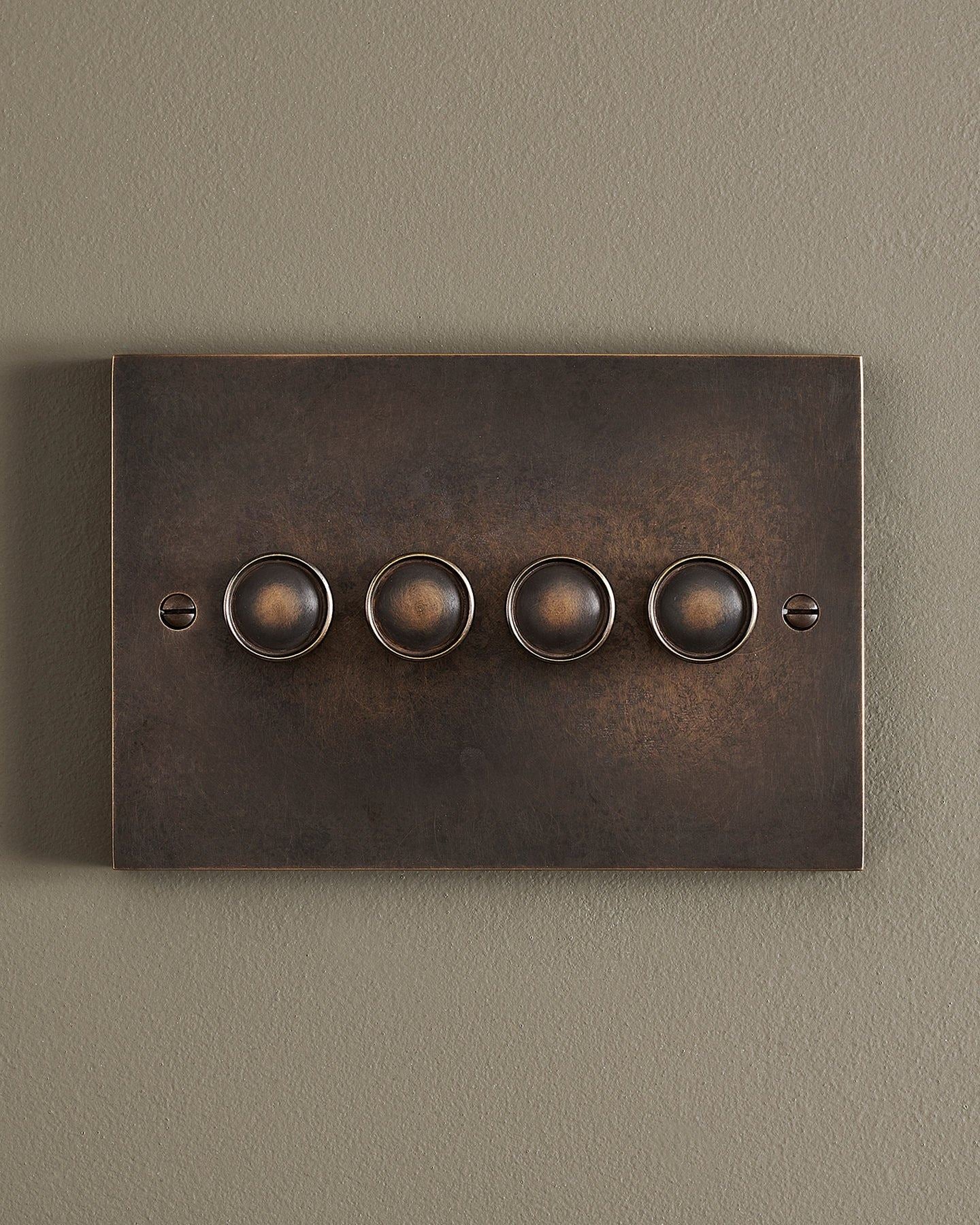 A straight-on view of a 4 gang box dimmer switch in a dark oxidised brass finish.
