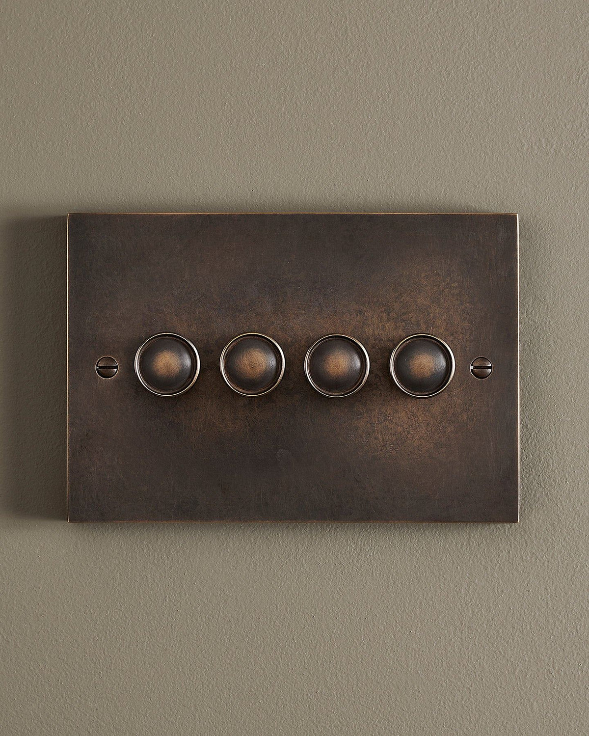 A straight-on view of a 4 gang box dimmer switch in a dark oxidised brass finish. TEST