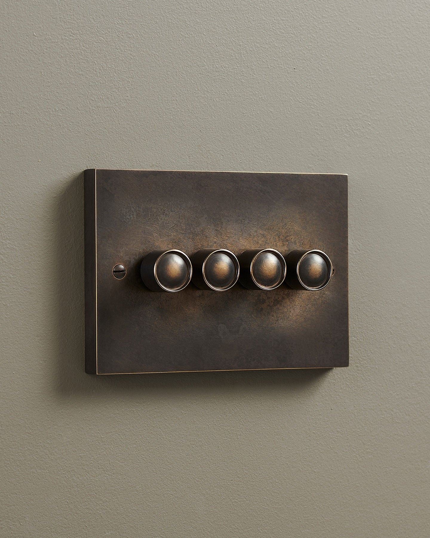 An oblique view of a 4 gang box dimmer switch in a dark oxidised brass finish.