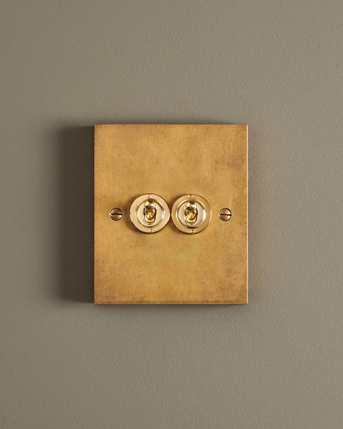 A straight-on view of a 2 gang box toggle switch in a warm burnished brass finish. TEST