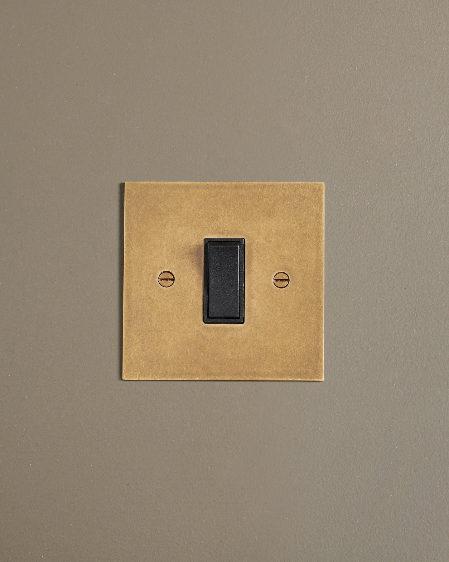A straight-on view of a classic 20 amp switch in a mottled aged brass finish.