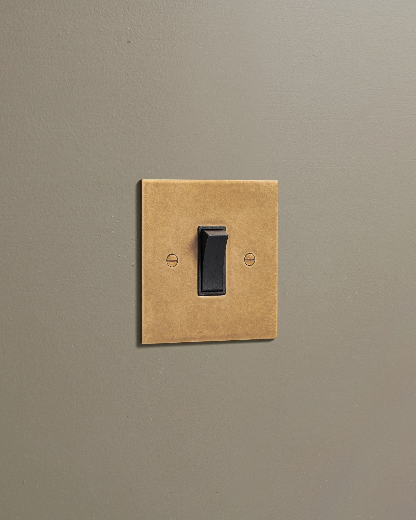 An oblique view of a classic 20 amp switch in a mottled aged brass finish.