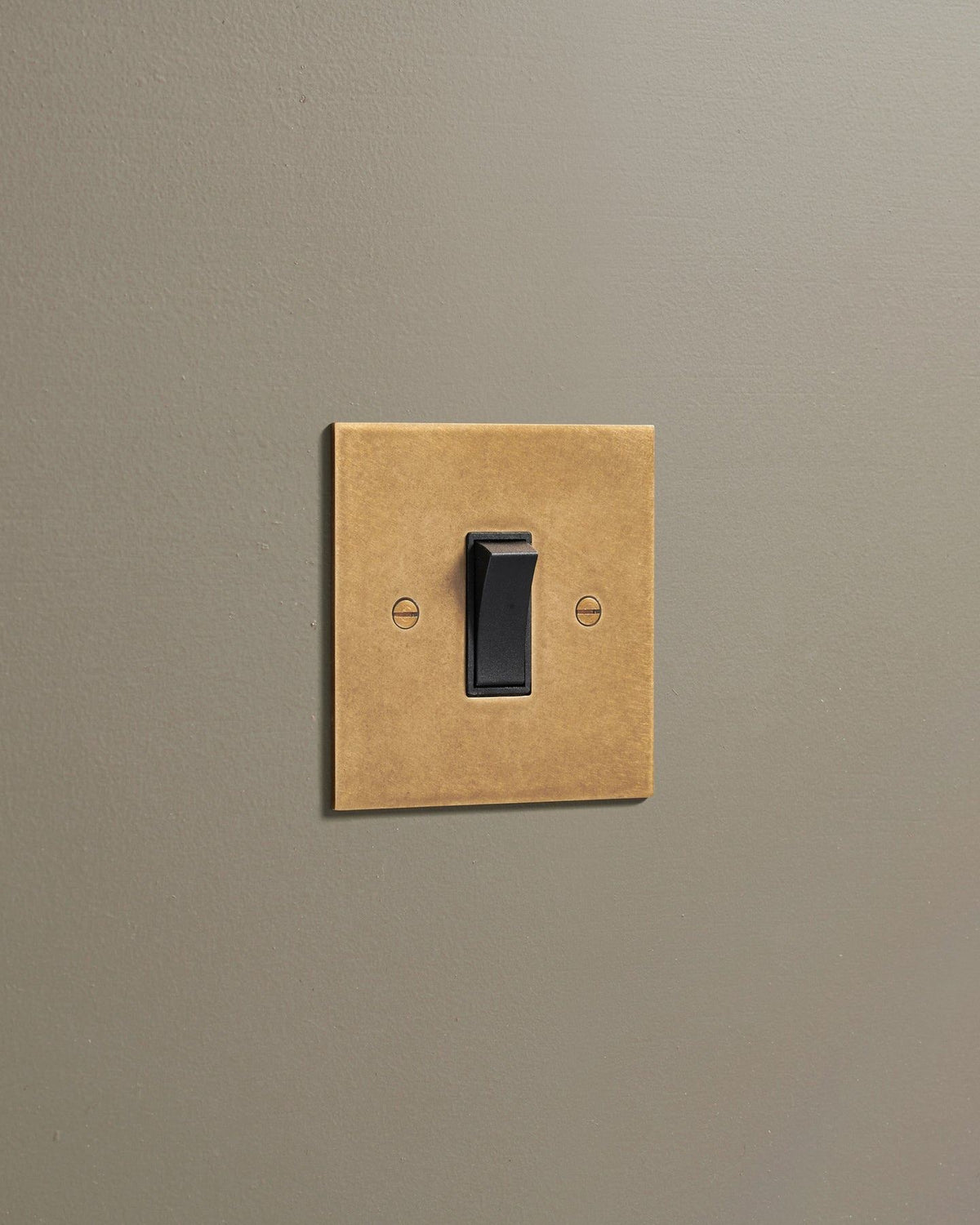 An oblique view of a classic 20 amp switch in a mottled aged brass finish. TEST