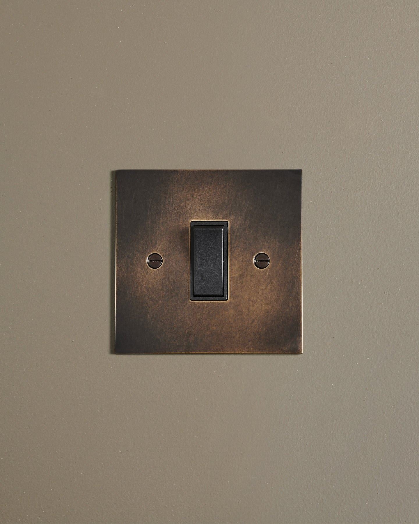 A straight-on view of a classic 20 amp switch in a dark oxidised brass finish.