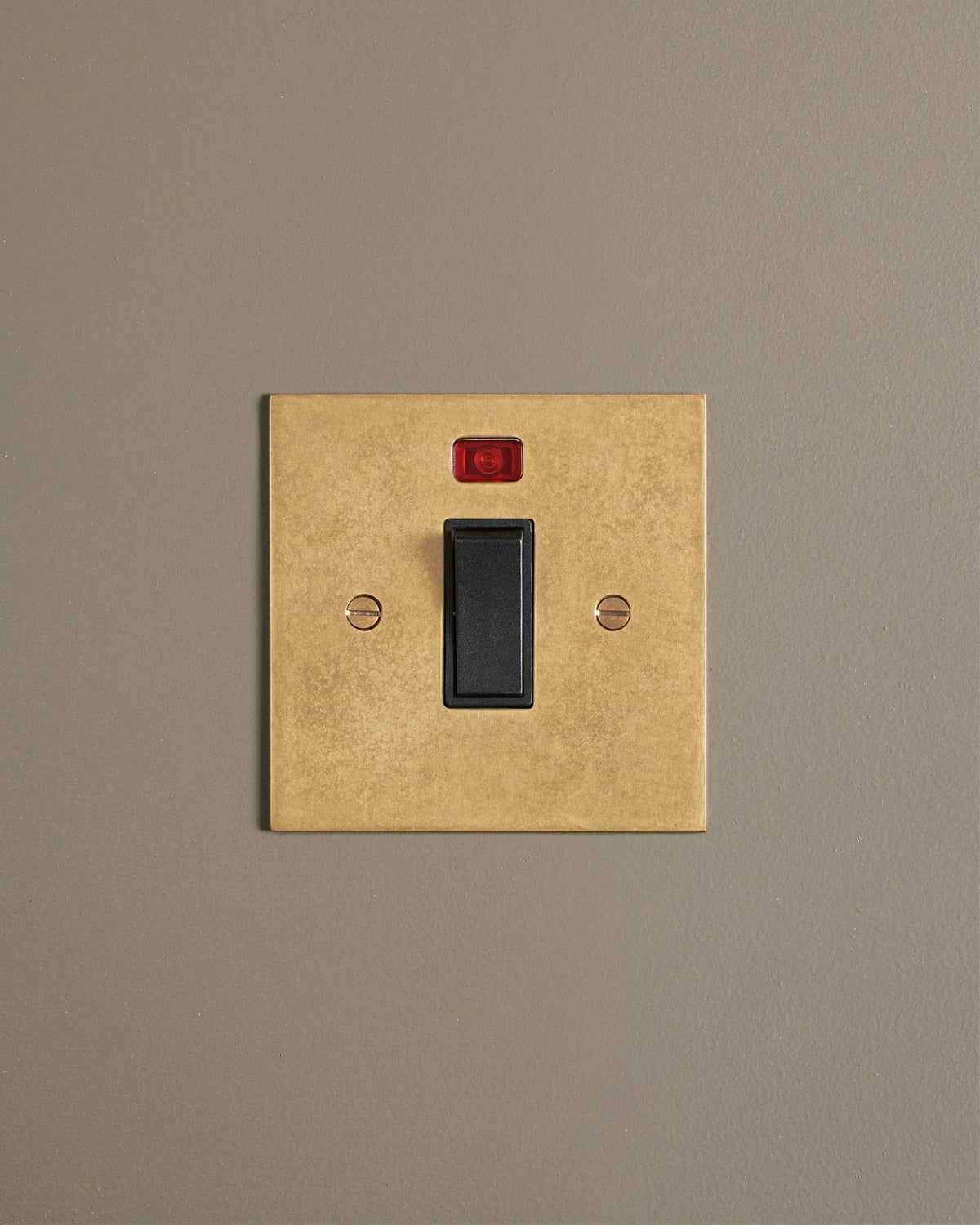 A straight-on view of a classic 32 amp cooker switch in a mottled aged brass finish. TEST