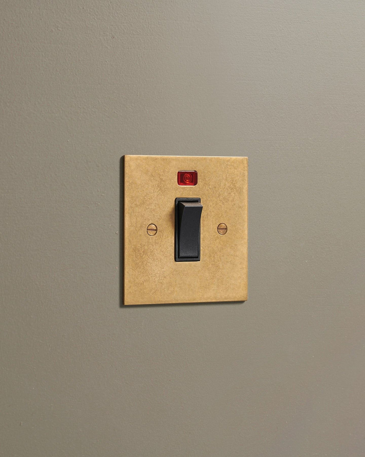 An oblique view of a classic 32 amp cooker switch in a mottled aged brass finish. TEST