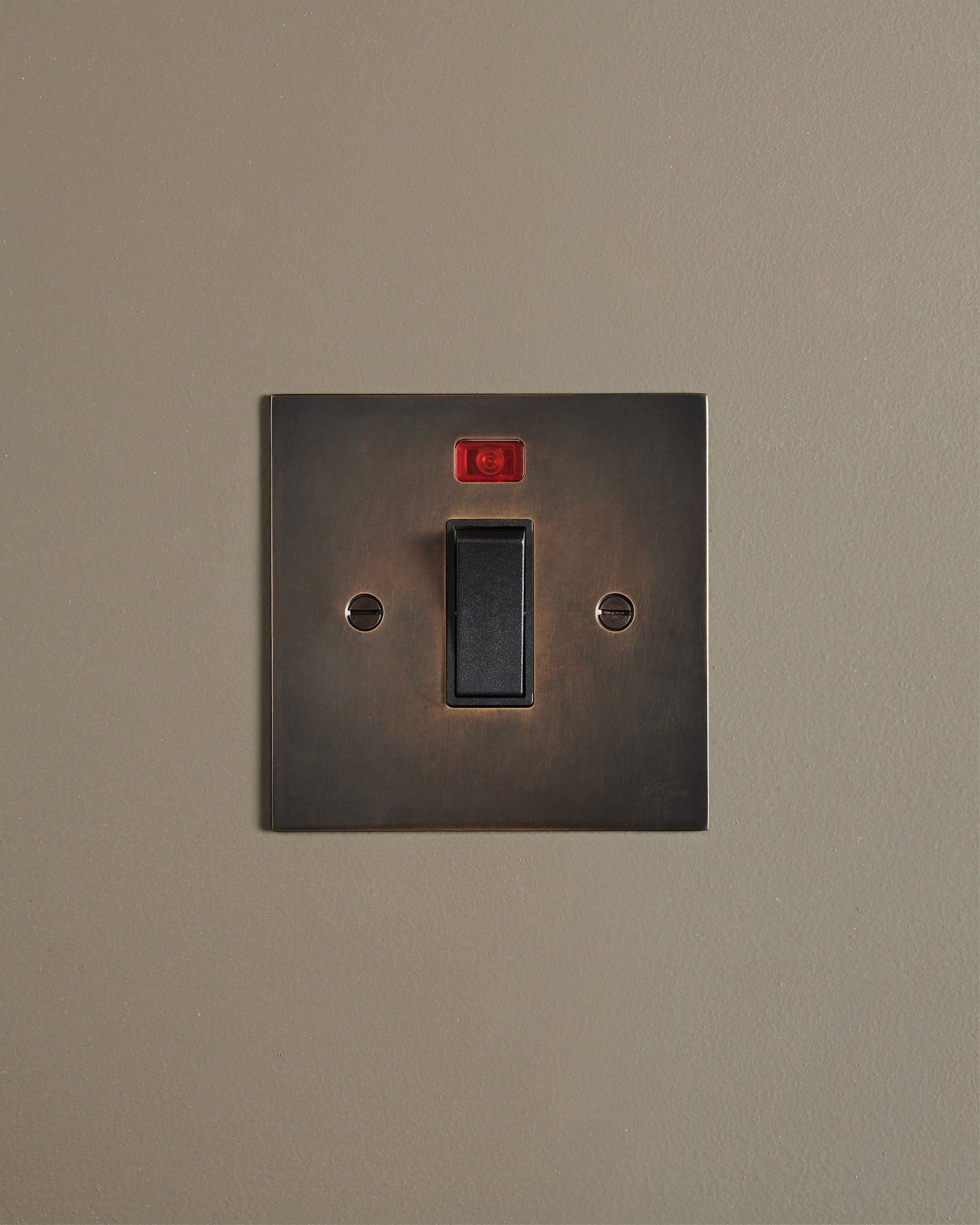 A straight-on view of a classic 32 amp cooker switch in a dark oxidised brass finish.