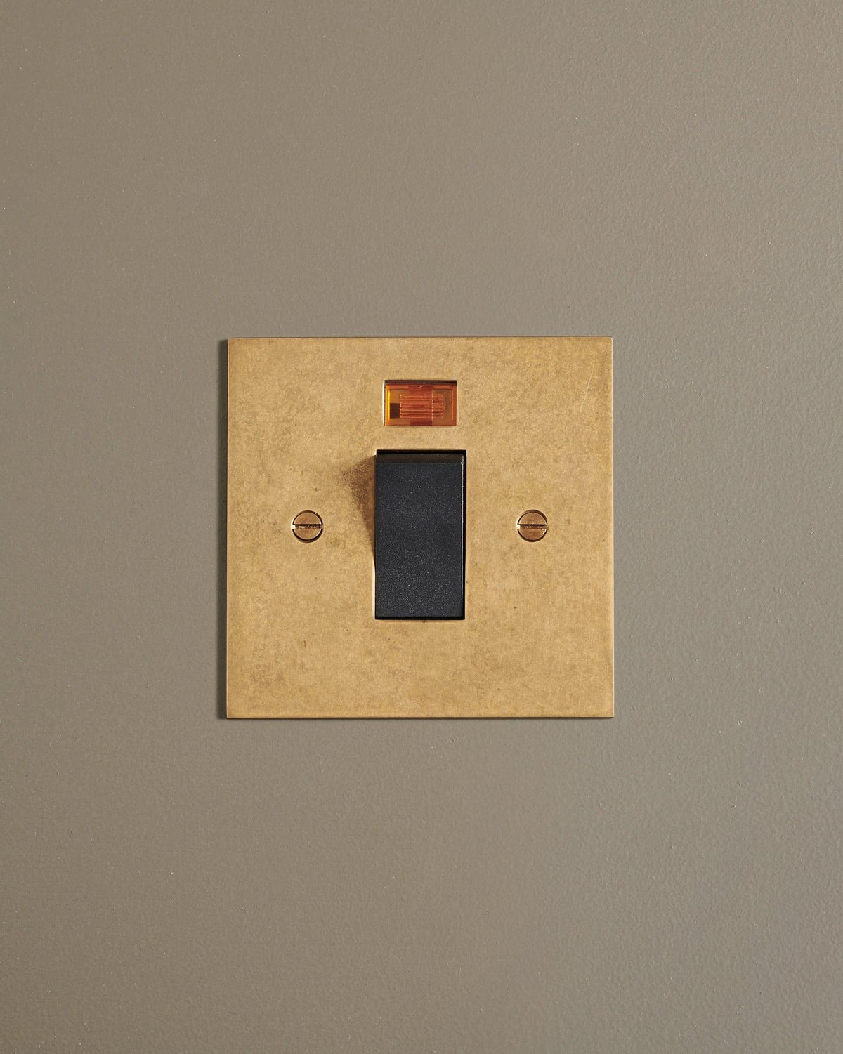 A straight-on view of a classic 45 amp cooker switch in a mottled aged brass finish. TEST