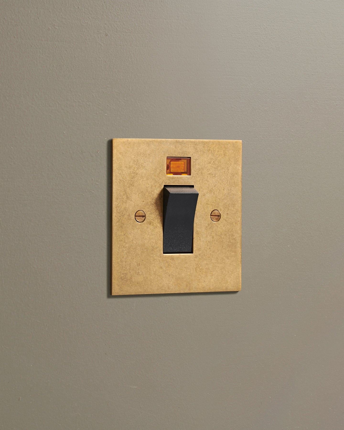 An oblique view of a classic 45 amp cooker switch in a mottled aged brass finish.