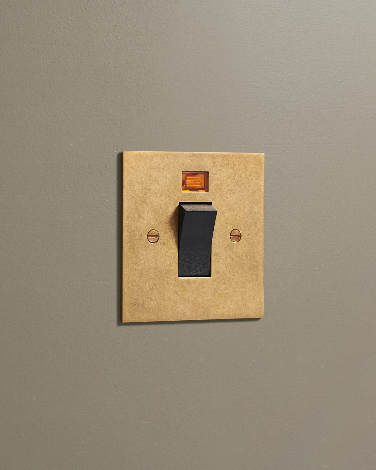 An oblique view of a classic 45 amp cooker switch in a mottled aged brass finish. TEST