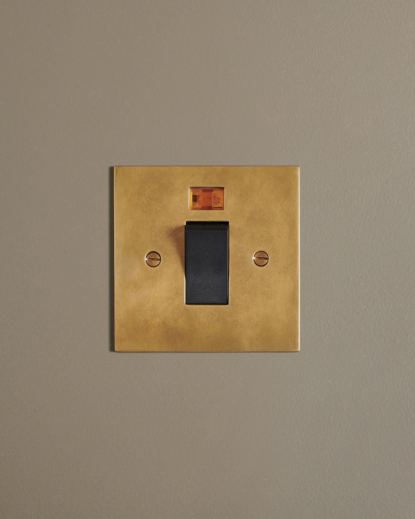 A straight-on view of a classic 45 amp cooker switch in a warm burnished brass finish.