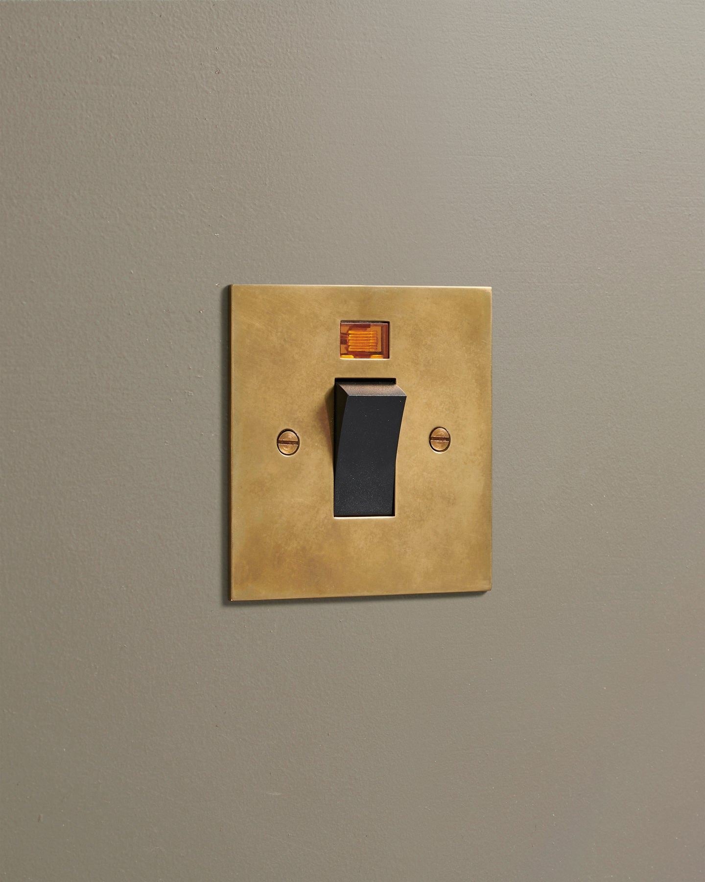 An oblique view of a classic 45 amp cooker switch in a warm burnished brass finish.
