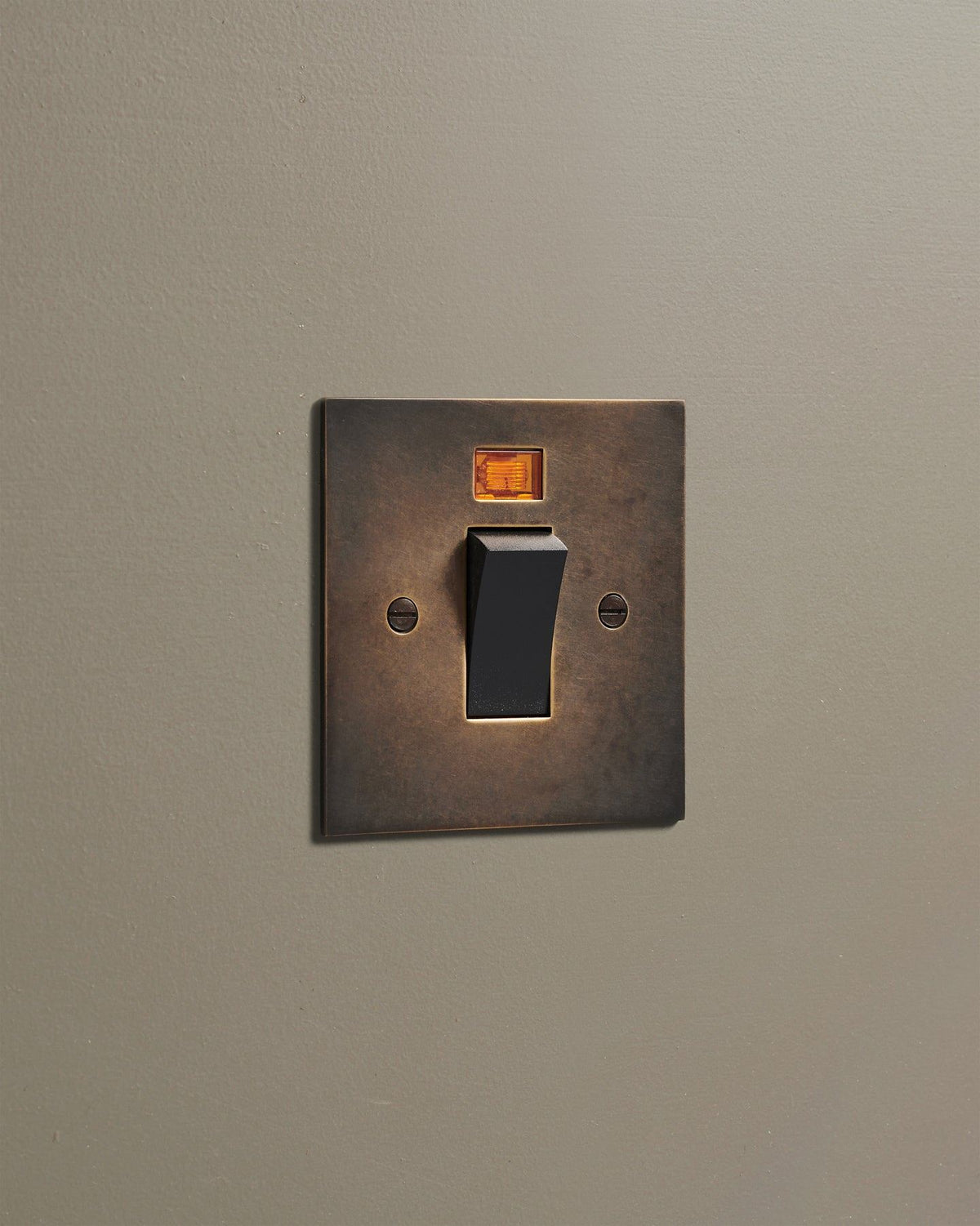 An oblique view of a classic 45 amp cooker switch in a dark oxidised brass finish. TEST