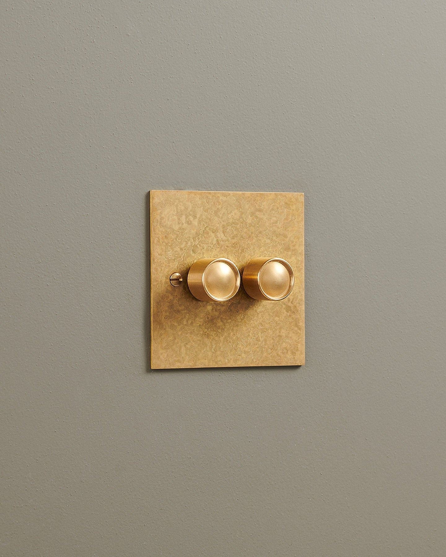An oblique view of a 2 gang classic dimmer switch in a mottled aged brass finish.