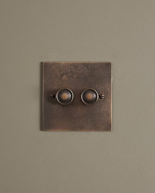 A straight-on view of a 2 gang classic dimmer switch in a dark oxidised brass finish.