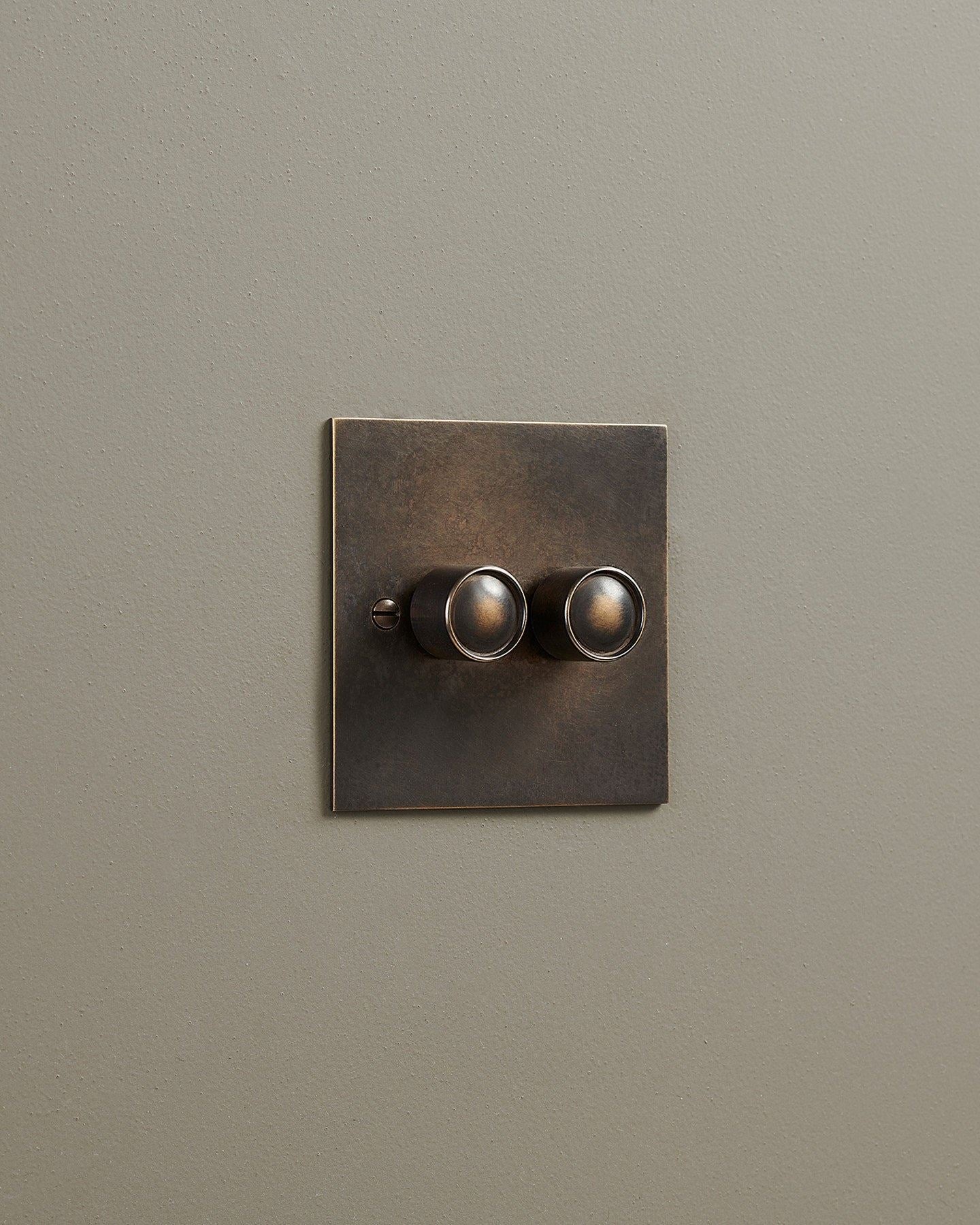 An oblique view of a 2 gang classic dimmer switch in a dark oxidised brass finish.