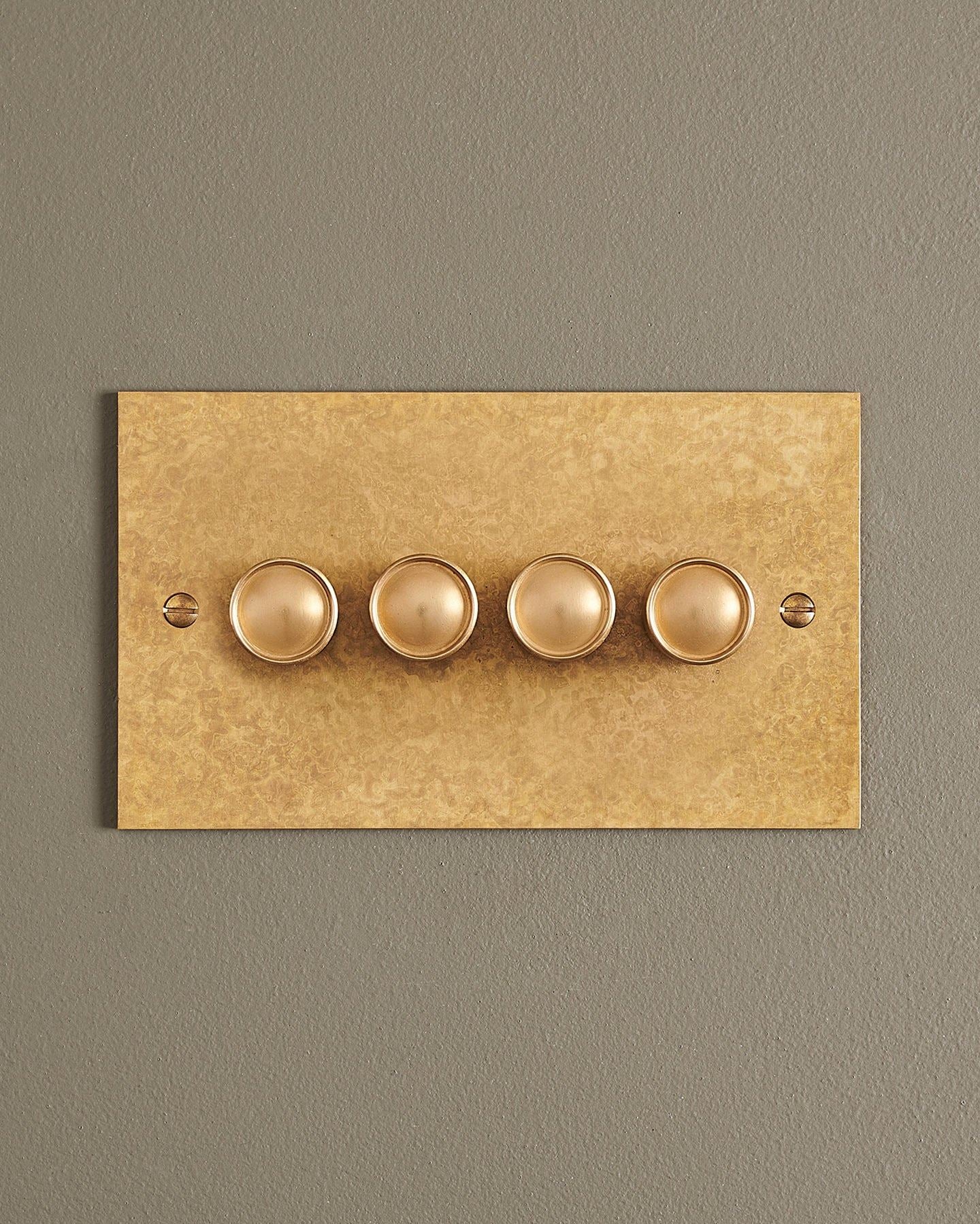 A straight-on view of a 4 gang classic dimmer switch in a mottled aged brass finish.