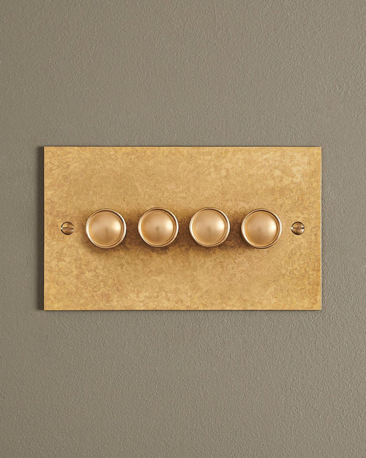 A straight-on view of a 4 gang classic dimmer switch in a mottled aged brass finish.